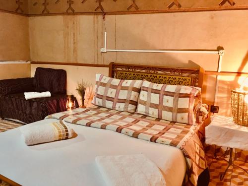 a bedroom with a large bed and a chair at Hôtel panoramique de la vallée in Aït Idaïr