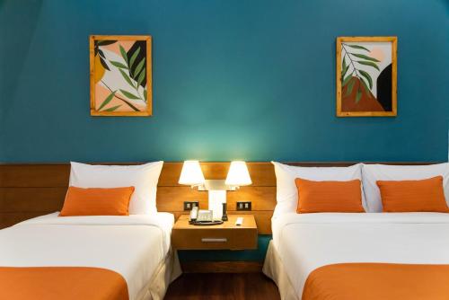 two beds in a hotel room with blue walls at Giraffe Boutique Hotel in Baguio