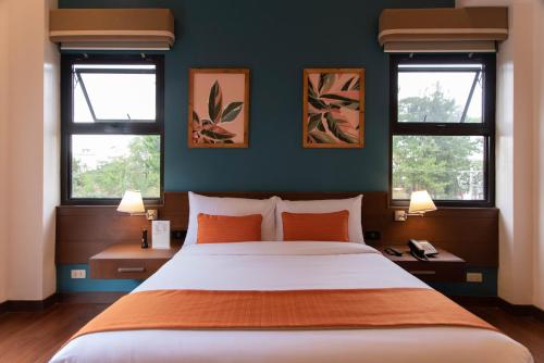 a bedroom with a large bed with two windows at Giraffe Boutique Hotel in Baguio