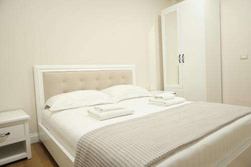 a white bedroom with a white bed with a mirror at Hotel Taverna Zisi in Ersekë