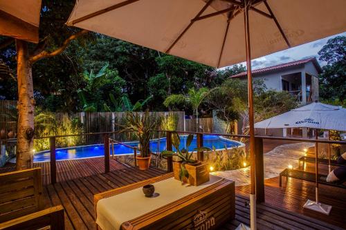 a patio with a table and an umbrella and a pool at Pousada Alecrim do Campo in Sao Jorge