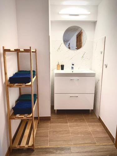 a bathroom with a sink and a shelf and a mirror at Noclegi przy Gołębiarce in Wleń