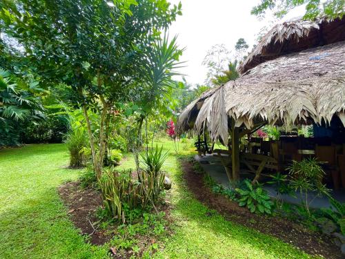 a restaurant with a thatched roof and a yard at Wildlife Lodge Cahuita in Cahuita