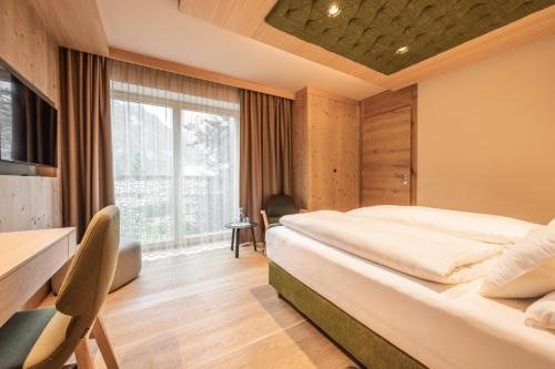a hotel room with a bed and a desk and a window at Hotel Kristall - Adults only in Leutasch