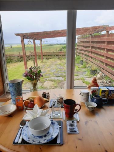 a table with a plate of food and a view of a field at Fabulous location with sea and castle view - NC500 in Keiss