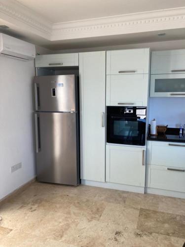 a kitchen with a stainless steel refrigerator and white cabinets at Spectacular views from this villa in Lapta in Kérynia