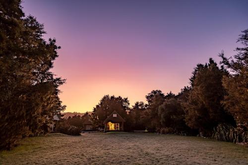 a house in the middle of a field at sunset at Kahere Retreat in Franz Josef