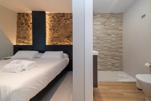 a bedroom with a white bed and a bathroom at Ultreia Seven Rooms by Adeloló in Santiago de Compostela