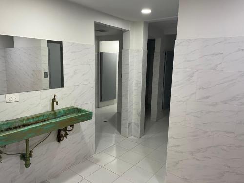 baño con lavabo verde y espejo en Hostal Casa Astromelia, en Bogotá