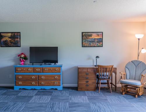 ein Wohnzimmer mit einem TV, einem Stuhl und einer Kommode in der Unterkunft Allen Lake Resort Richfield Springs Cooperstown in Richfield Springs