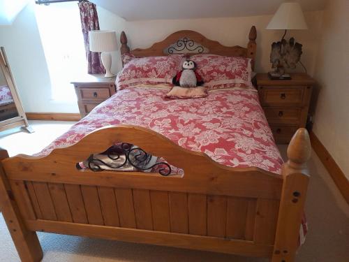 a bedroom with a wooden bed with a teddy bear on it at Berwick Hall Cottage in Moira