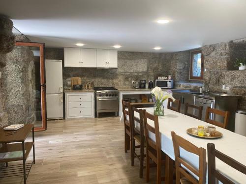 eine Küche mit einem Tisch und Stühlen sowie eine Küche mit weißen Schränken in der Unterkunft Quinta dos Mouras B&B in Rebordões