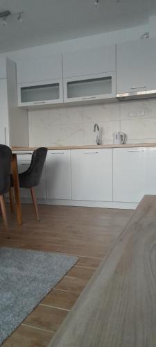a kitchen with white cabinets and a sink and a table at Apartmani Sunlight in Vrnjačka Banja