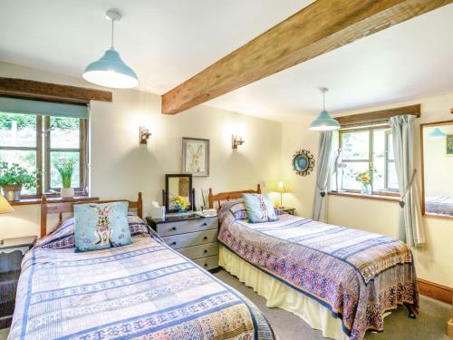 two beds in a room with two windows at Bwythyn Y Wennol in Beddgelert