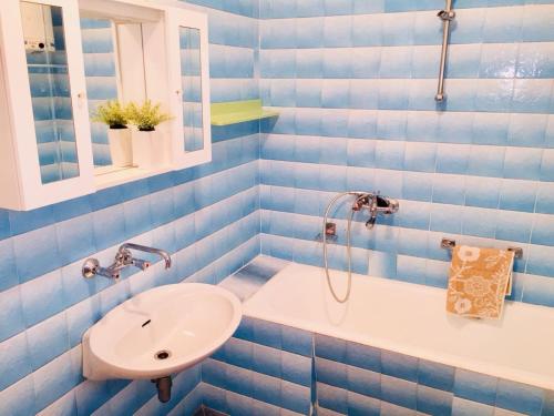 La salle de bains est pourvue de carrelage bleu, d'un lavabo et d'une douche. dans l'établissement Family friendly apartments with a swimming pool Kastel Stafilic, Kastela - 18062, à Kaštela
