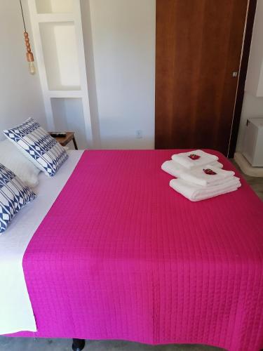 a pink blanket on a bed with two towels on it at Dona Maragô Pousada in Maragogi