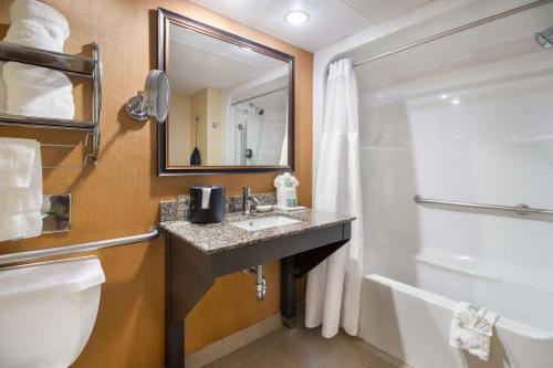a bathroom with a sink and a toilet and a mirror at Best Western Suites near Opryland in Nashville