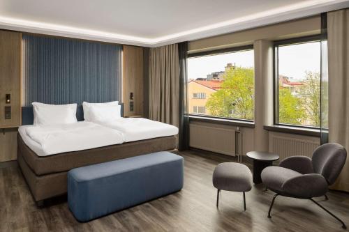 um quarto com uma cama, cadeiras e janelas em Radisson Blu Marina Palace Hotel, Turku em Turku