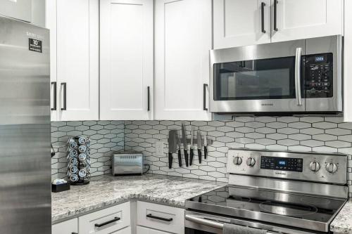 a kitchen with white cabinets and a stove and a microwave at Grand Oaks Terminal in the Heights in Tampa