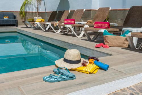 a hat and flip flops next to a swimming pool at Villa La marina in Nerja