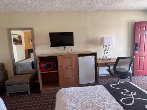 セントジョージにあるBudget Innのテレビ、デスク、椅子が備わるホテルルームです。