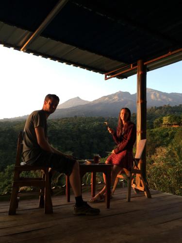 a man and a woman sitting at a table on a porch at Rinjani Houseboon in Senaru