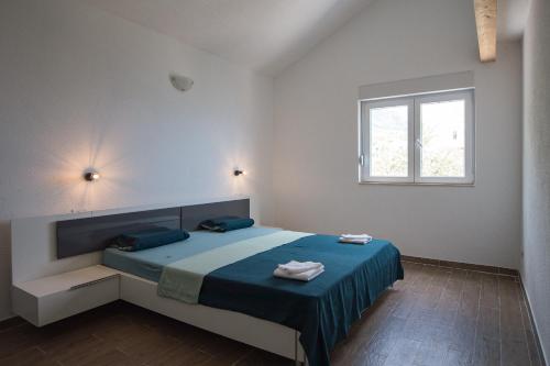 a bedroom with a bed with blue sheets and a window at Villa Stipe in Jesenice