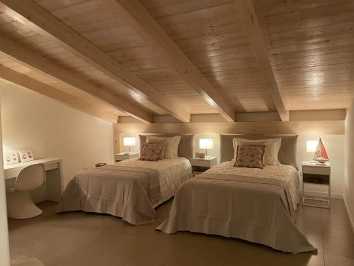 two beds in a room with wooden ceilings at Villa Fiorentino in Rossano