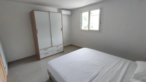 a white bedroom with a bed and a window at Les Eaux Turquoise in Terre-de-Haut