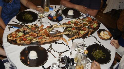 a group of people sitting at a table with a pizza at Le Grand Bleu in Andilana