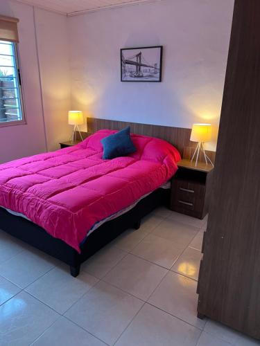 1 cama grande de color rojo en una habitación con 2 lámparas en Apart Del Este 1, en Paysandú