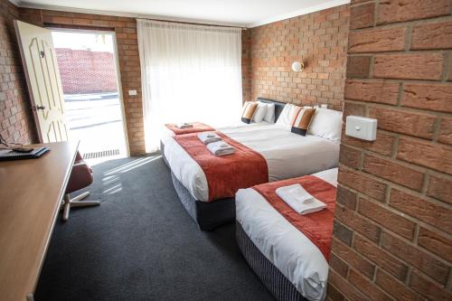 a hotel room with two beds and a brick wall at Moama Motel in Moama