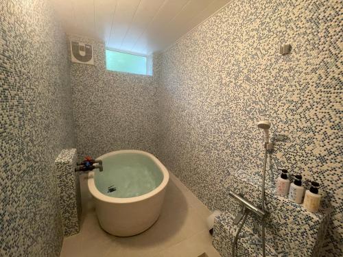 a bathroom with a bath tub and a sink at Kusatsu Onsen Kusatsu Hotel1913 in Kusatsu
