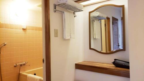 a bathroom with a sink and a mirror and a tub at AoAwo Naruto Resort in Naruto