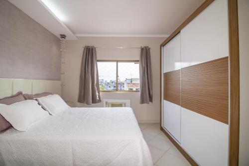 a bedroom with a white bed and a window at Apartamento Moderno com Terraço à 4Km do Consulado USA in Porto Alegre