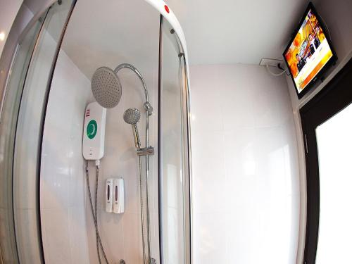 a shower in a bathroom with a mirror and a tv at MD Grand Hotel Nakhon in Nakhon Si Thammarat