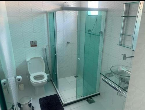 uma casa de banho com um WC e uma cabina de duche em vidro. em Excelente casa com Piscina em Camaçari