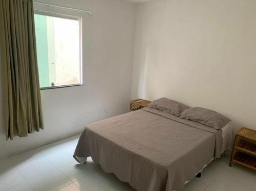 um quarto branco com uma cama e uma janela em Excelente casa com Piscina em Camaçari