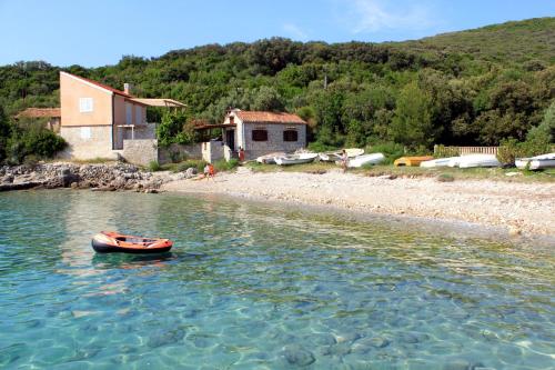 ein kleines Boot im Wasser neben einem Haus in der Unterkunft Seaside holiday house Miholascica, Cres - 8073 in Martinšćica