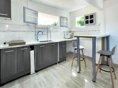 a kitchen with gray cabinets and a counter with stools at Villa Autre Bord in Case-Pilote