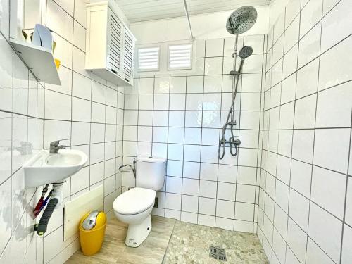 a bathroom with a toilet and a sink and a shower at Villa Autre Bord in Case-Pilote