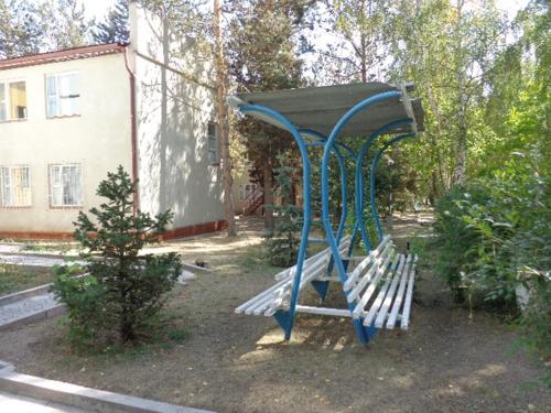 a blue bench in a yard with a building at Guest House at DO Altyn - Kum in Chon-Sary-Oy
