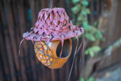a pink and yellow bird feeder hanging from a fence at Le Charme Polynésien proximité plage et commerces in Punaauia