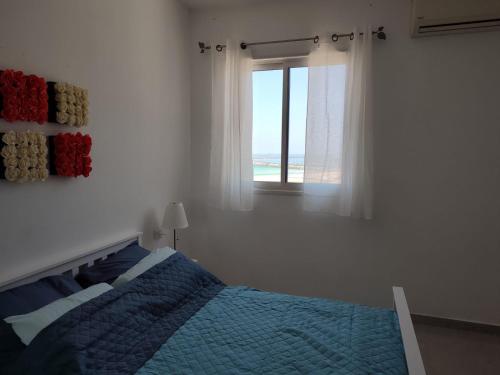 - une chambre avec un lit bleu et une fenêtre dans l'établissement Lovely three-room apartment above the promenade, à Ashdod