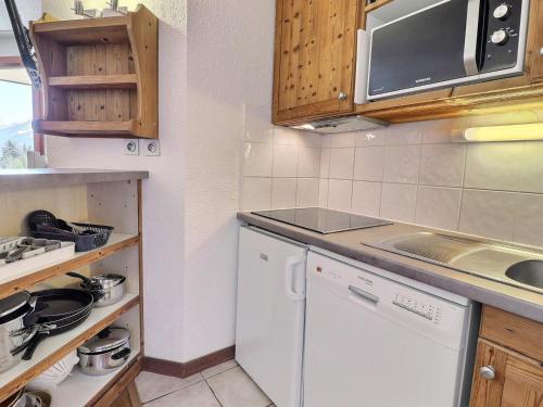 La cuisine est équipée d'un lave-vaisselle blanc et d'un four micro-ondes. dans l'établissement Charmant Appartement à La Tania - 6 pers, skis aux pieds, proche commodités - FR-1-182A-10, à Courchevel