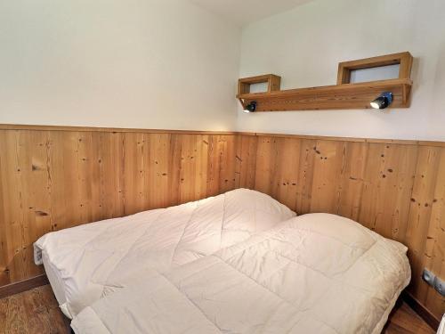 Bett in einem Zimmer mit einer Holzwand in der Unterkunft Appartement La Tania, 2 pièces, 4 personnes - FR-1-182A-14 in Courchevel