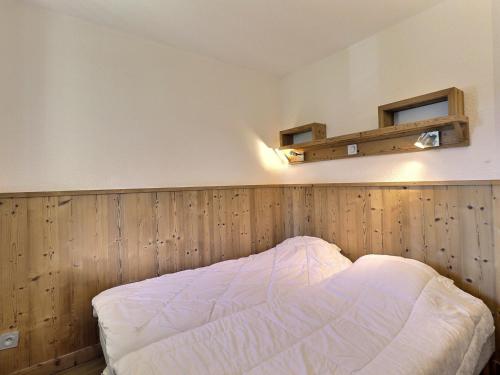 een bed in een kamer met een houten muur bij Appartement La Tania, 2 pièces, 4 personnes - FR-1-182A-27 in Courchevel