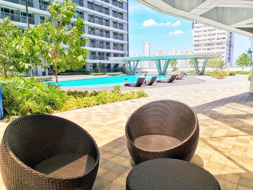 2 chaises en osier et une piscine dans un bâtiment dans l'établissement Stylish 1 Bedroom Condo Unit with Perfect Pool View Balcony at Fame Residences, à Manille