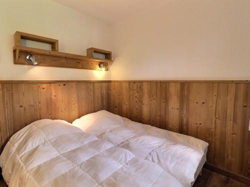 un lit dans une chambre avec un mur en bois dans l'établissement Charmant 2P au cœur des 3 Vallées, skis aux pieds, balcon Est, 4 pers., La Tania - FR-1-182A-25, à Courchevel