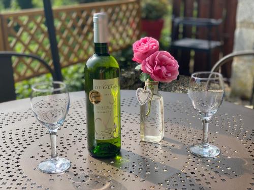 a bottle of wine and two glasses on a table at Gîte la canopée à Duras - Piscine in Duras